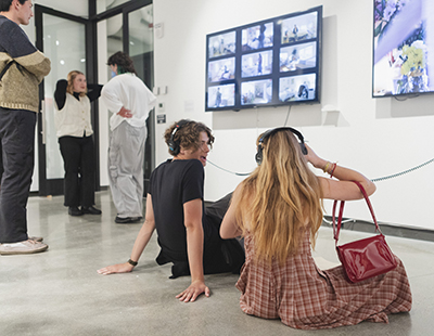 Students sit on the floor of the Jacob Lawrence Gallery looking at art on the walls. 