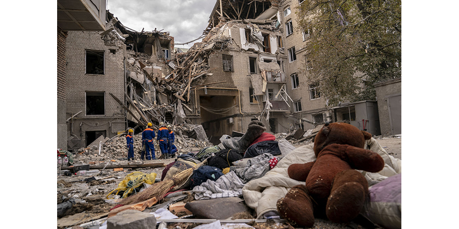 A destroyed street in Ukraine, with a teddy bear in a pile of rubble in the foreground.