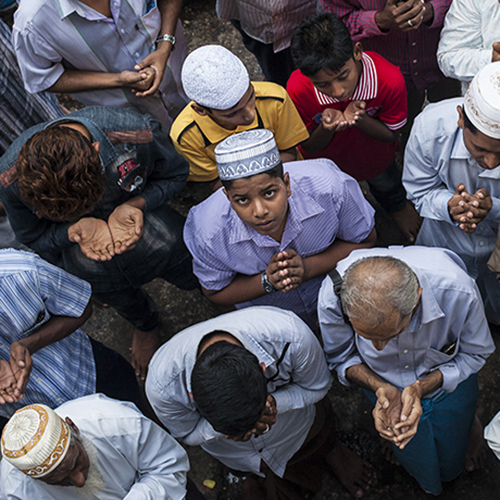 Group of Muslims in Myanmar in prayer, photographed from above.