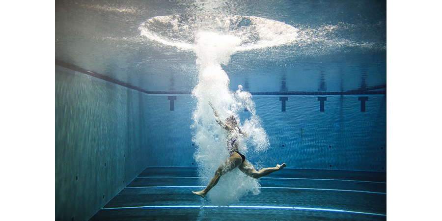 A swimmer in a pool, taken underwater.