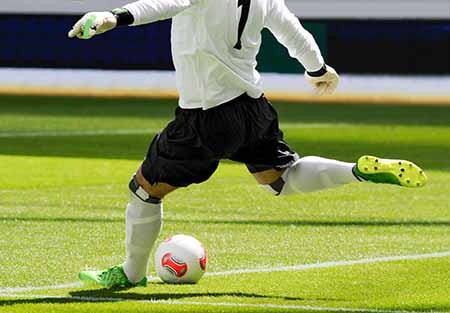 Soccer player kicking a ball on a soccer field. 