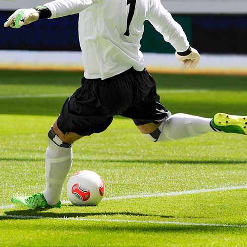 A soccer player kicking a ball. 