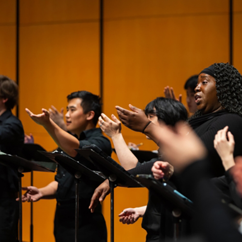 Singers lifting their arms as they sing.