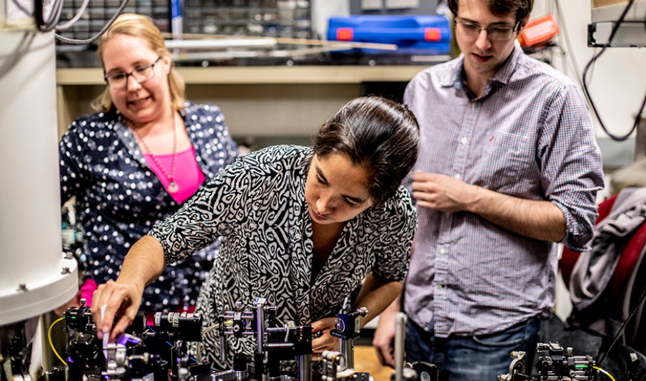 Kai-Mei Fu (center) adjusts equipment for a quantum experiment. Fu's research group studies the quantum-level properties of crystalline materials.