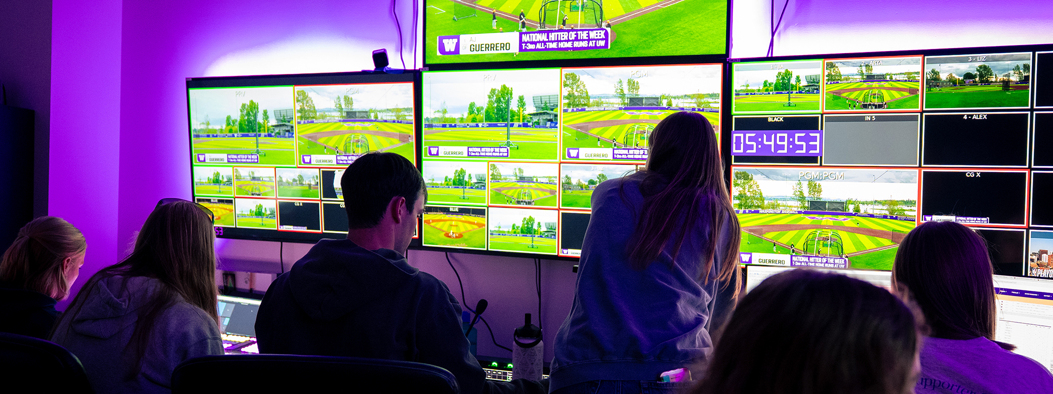 The StudentU team looks at a series of large screens in the broadcast control room. 