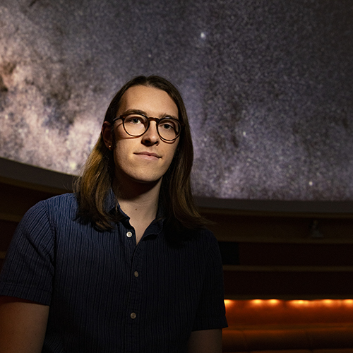 Max Frissell in the UW Planetarium, with the starry "sky" visible behind him.