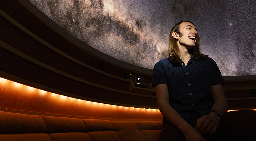 Max Frissell in the UW Planetarium, with the starry "sky" visible behind him.