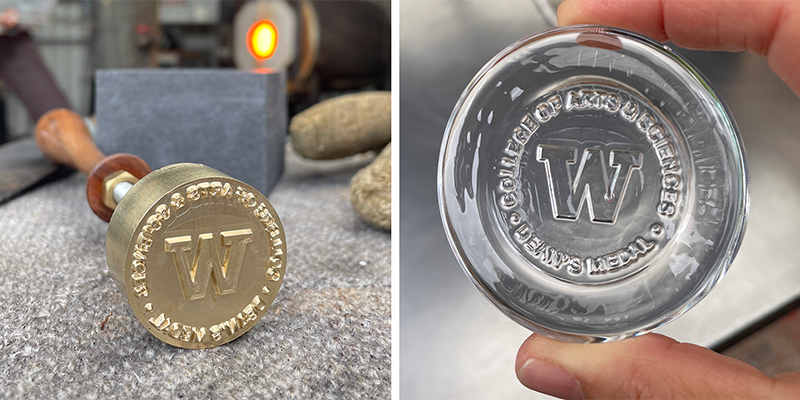 A metal stamp with a "W" and text on it, next to a clear round disk of glass, a sample to show how glass will look after it is stamped. 