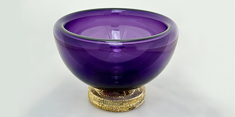 close up of a purple blown-glass bowl with a gold-leaf on its "foot."
