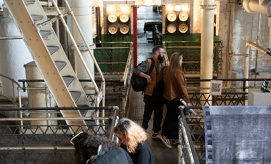People walk through an exhibition in an industrial-looking former steam plant.