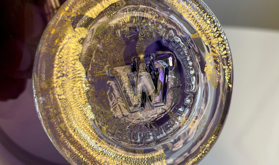 Purple and gold glass bowl with the University of Logo on the base