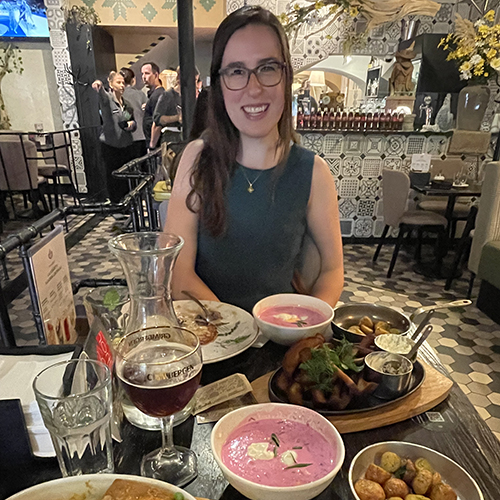 Sarena Sabine at a restaurant in Lithuania, with bowls of various food crowding the table.