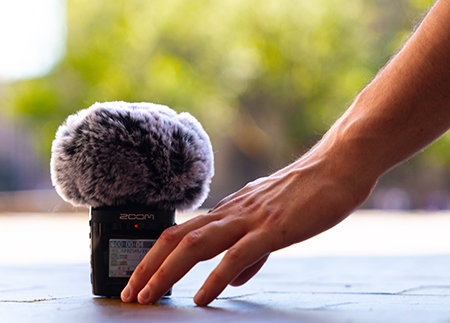 A hand sets a microphone with a fluffy grey cover onto the brick-covered ground of UW's Red Square. 