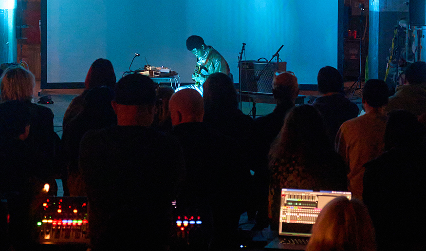Performer on stage with instrument that responds to technology.
