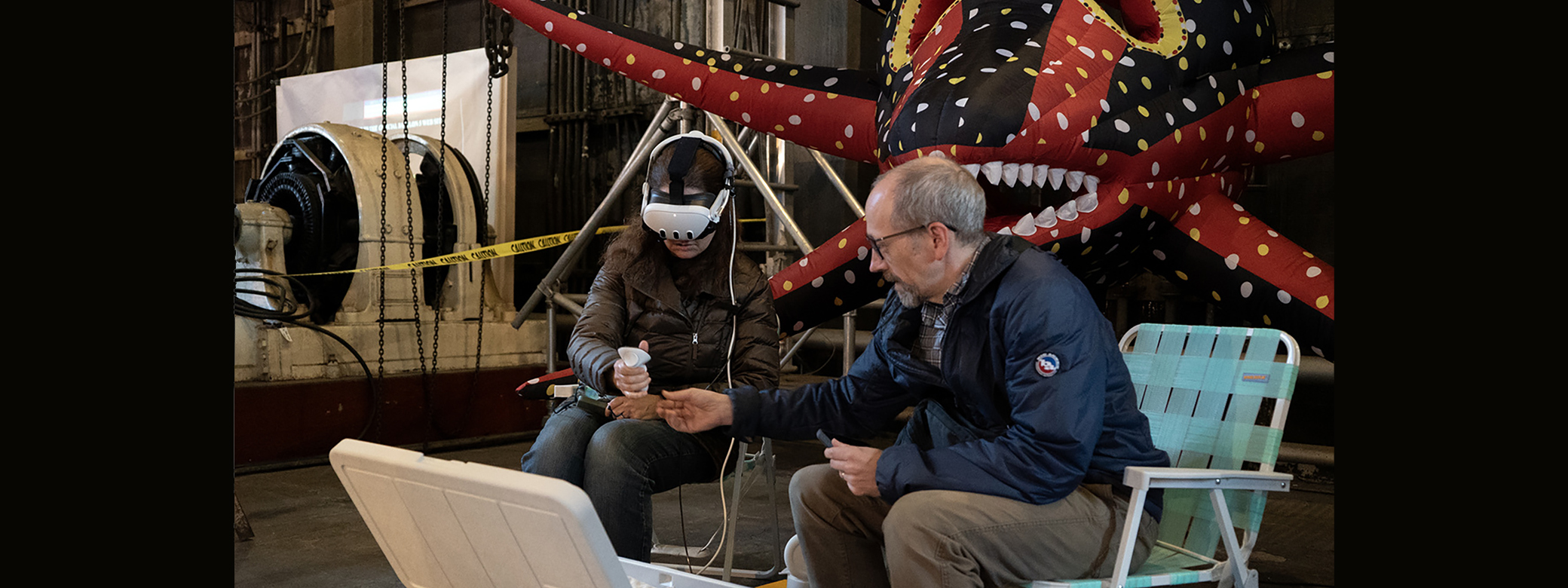 Person wearing virtual reality headset while another person speaks to them. 