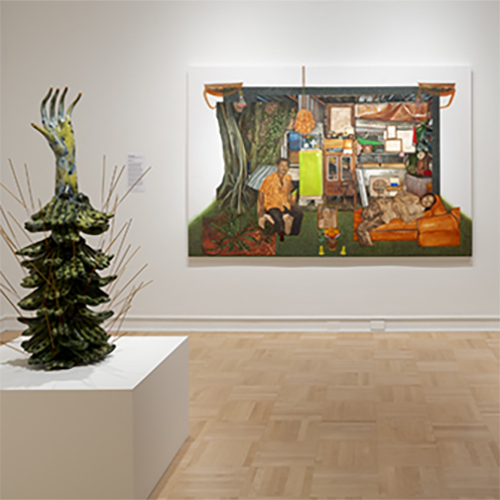 Artwork from Spirit House exhibition - a wall artwork and a sculpture on a white pedestal. 