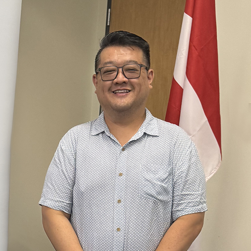 Johnathan Tran at a conference in Canada, with a Canadian flag in the background.