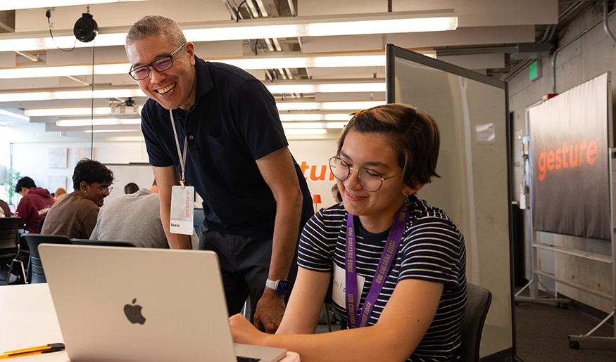 Kevin Mihata talks with a UW student in the gesture program as they look at the student's laptop screen.