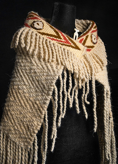 A woven shawl with a decorative band at the neck.