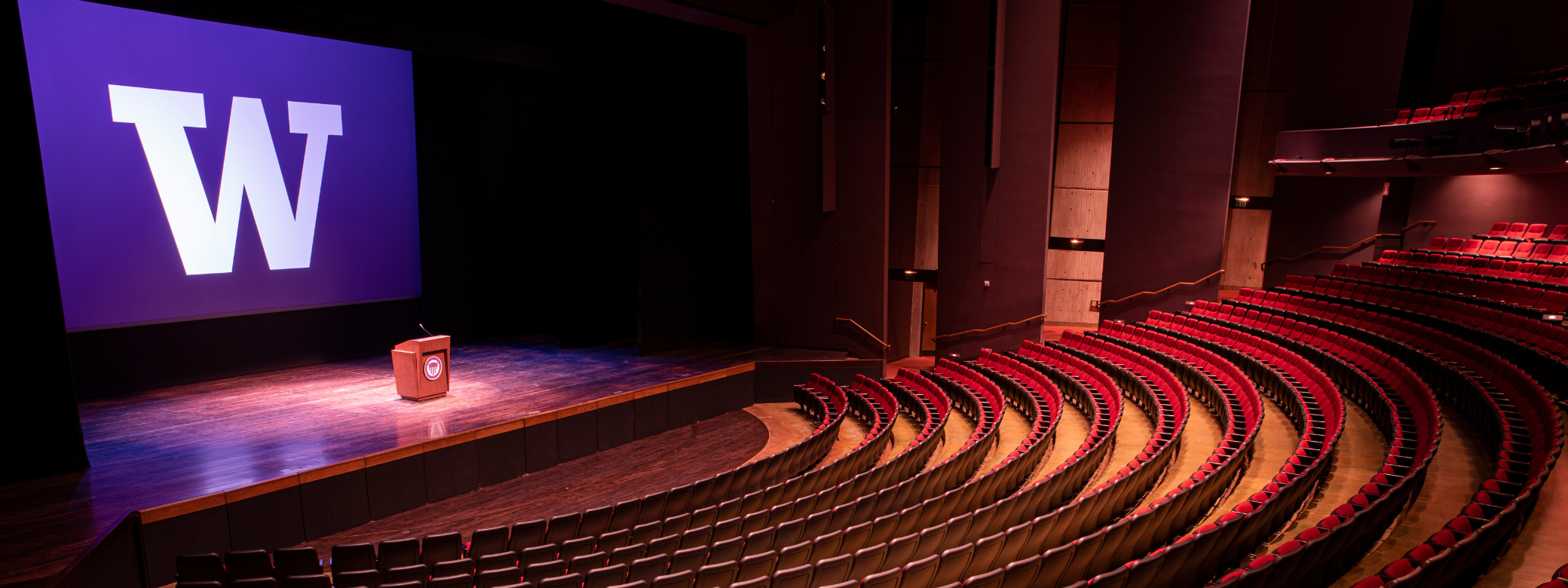 Meany Center stage with the University of Washington's "W" letter block in white on a purple background on the stage screen