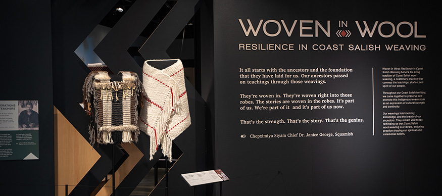 Entrance to the Woven in Wool exhibit at the Burke Museum, with woven garments and introductory text. . 
