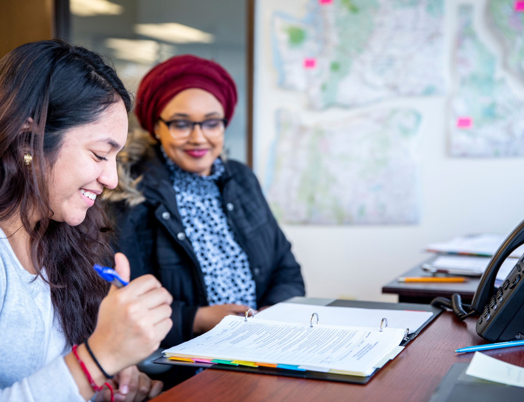 People looking at a binder filled with pages