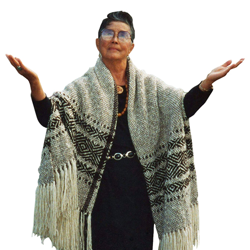 Vi Hilbert in a woven cape, with her hands raised.