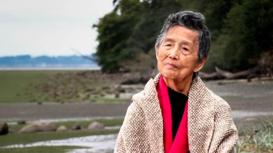 Vi Hilbert stands along the shoreline.