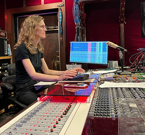 Andrea Roberts working at the console in a recording studio.