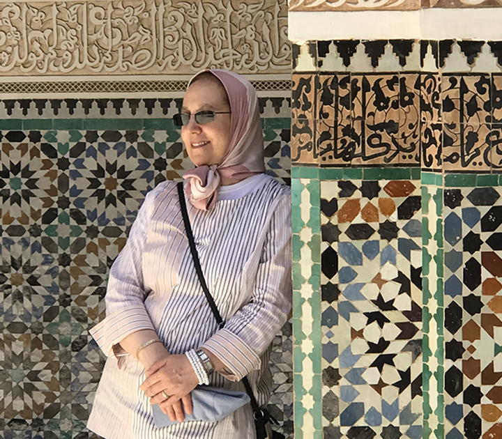 Professor Amina Moujtahid in Morocco while teaching a study abroad course, surrounded by colorful mosaic walls