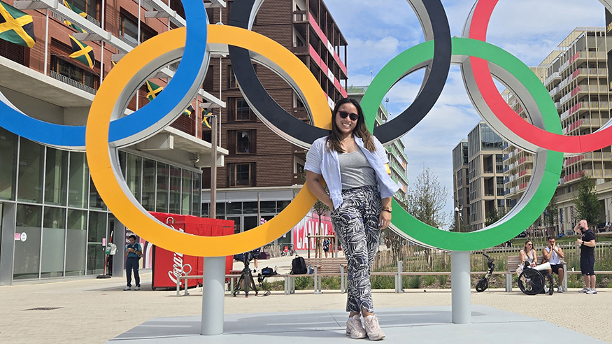Thuc Nhi Nguyen standing in front of a colorful statue of the Olympic Games interlocked rings logo.