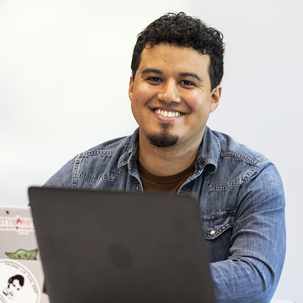 Student with laptop smiling at camera