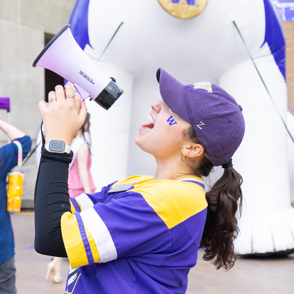 student with bullhorn in purple hat