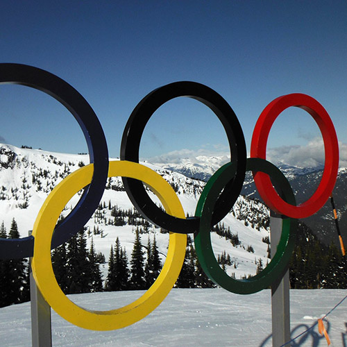Sculpture of colorful Olympic rings with snowy mountains in background