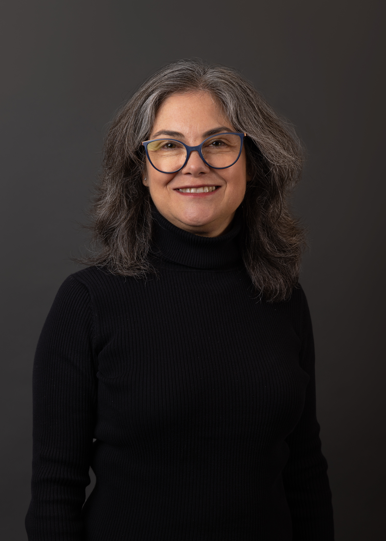 A smiling woman in glasses and a black turtleneck.