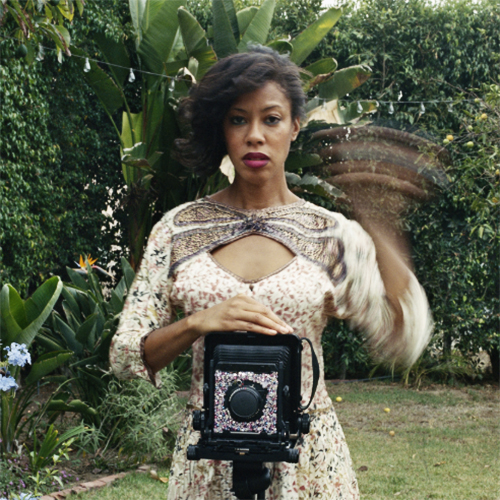 Photographer Deanna Lawson captures a photo of herself standing behind large camera on a tripod.