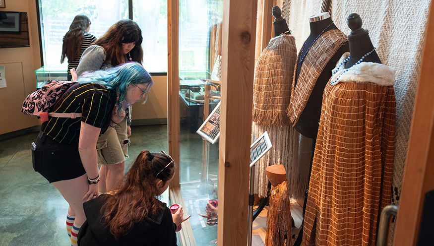 Students look at clothing in a display case at the Duwamish Longhouse and Cultural Center