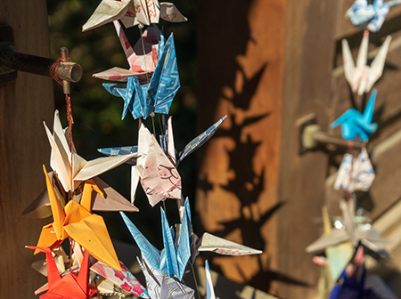 Colorful origami cranes hanging in a vertical row.