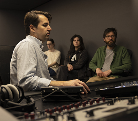 Andrew Munsey sits at the recording controls while three students observe,