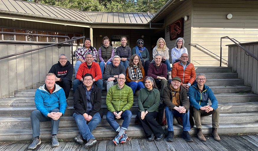 A group of people pose on a wooden staircase.