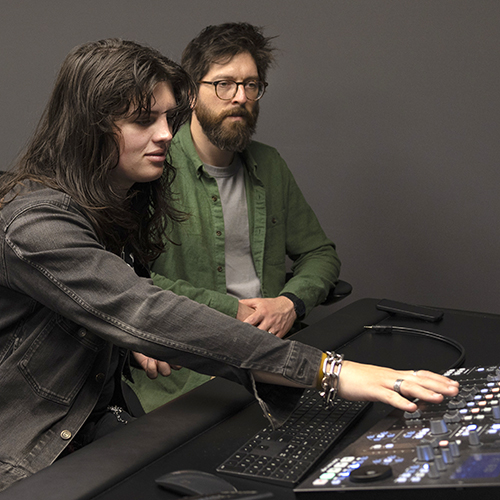 Two students working with recording equipment in a recording studio.