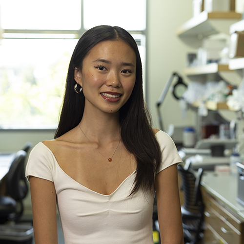 Hunter Jung in a research lab, with shelves of lab equipment on either side of her.