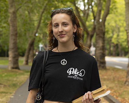 Piper Sorensen walking across the UW campus, holding books.
