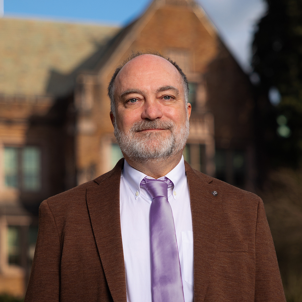 Portrait of Richard Wright wearing a coat and tie in front of campus building