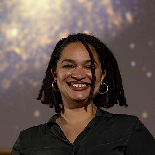 Arianna Long in the UW Planetarium, with galaxies projected on the screen overhead.