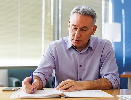 Dow Constantine seated at a desk, writing.