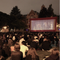 Students sit on the Quad to watch a movie at night