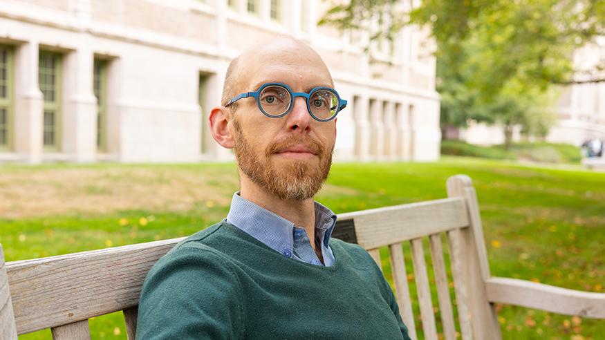 Colin Marshall sitting on a wooden bench on the UW campus.