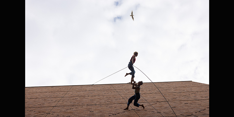 Two dancers dance along the side of Meany Hall. 