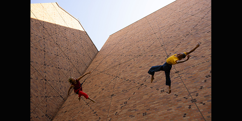 Two dancers dance along the side of Meany Hall. 